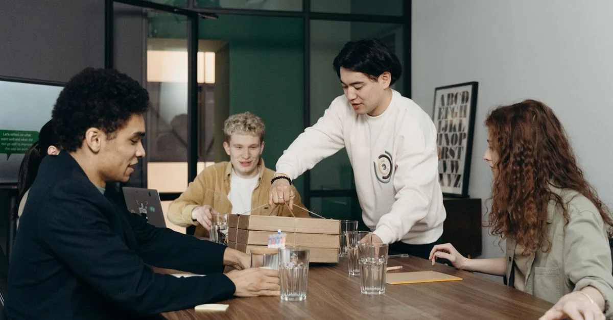 Un groupe diversifié de jeunes professionnels profitant d'une pause déjeuner ensemble dans un environnement de bureau moderne.